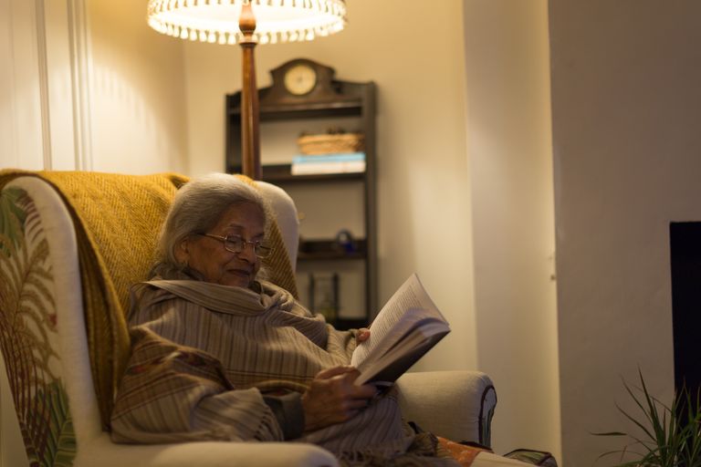 Lady reading a booking by lamplight