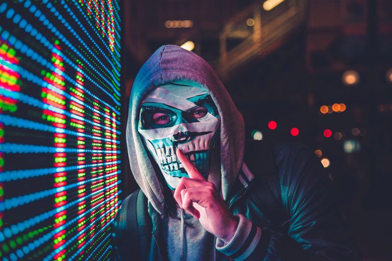 A hacker wearing a mask next to a screen