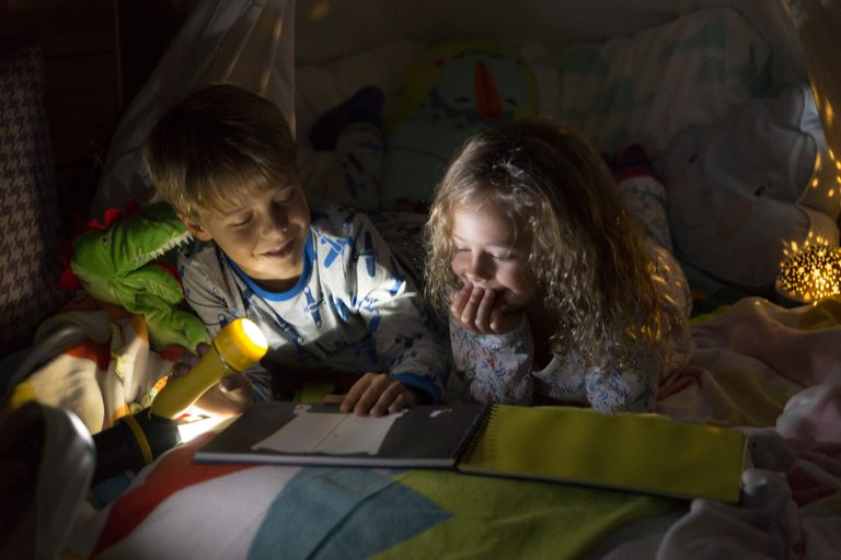 Children reading under torchlight