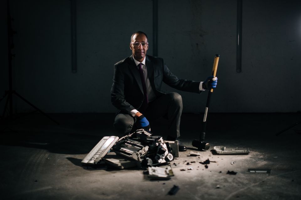 Actor crouching over smashed fax machine