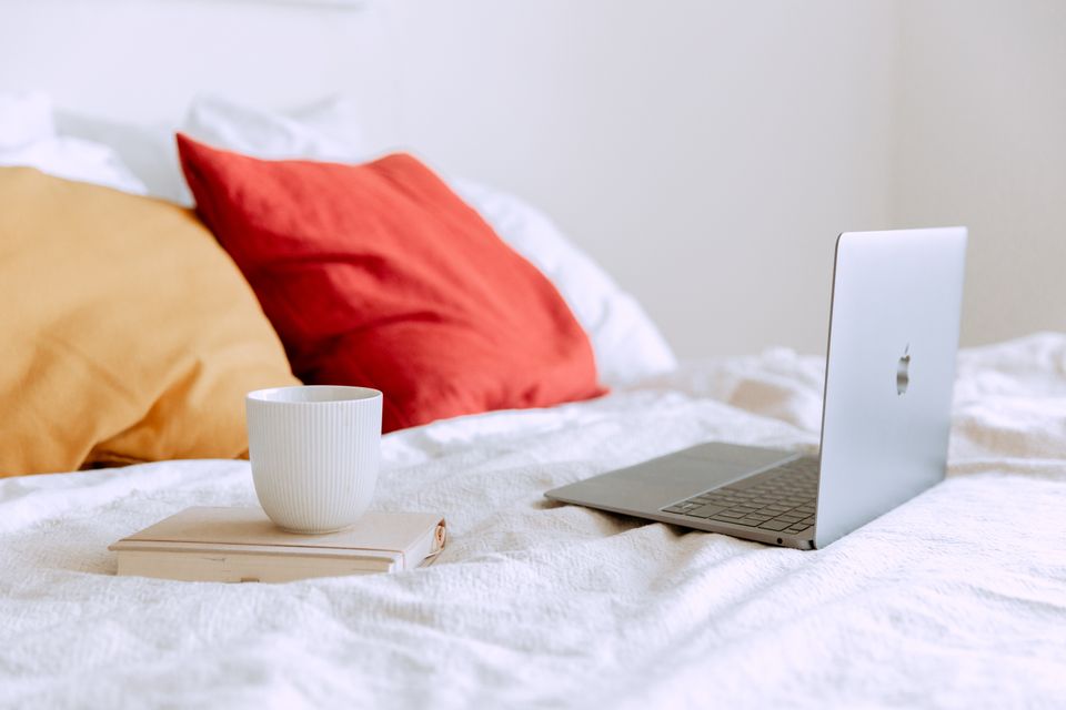 Laptop and coffee cup on a bed
