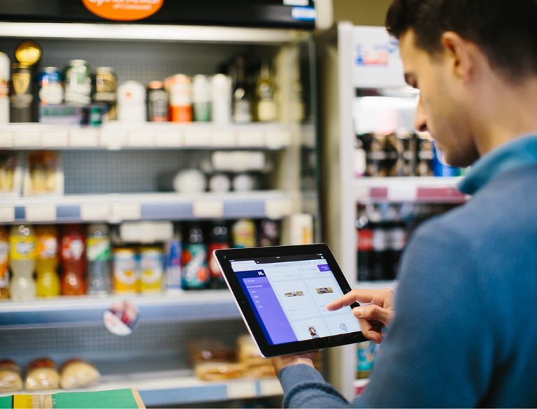 Shop owner using food ordering platform to stock shelves.